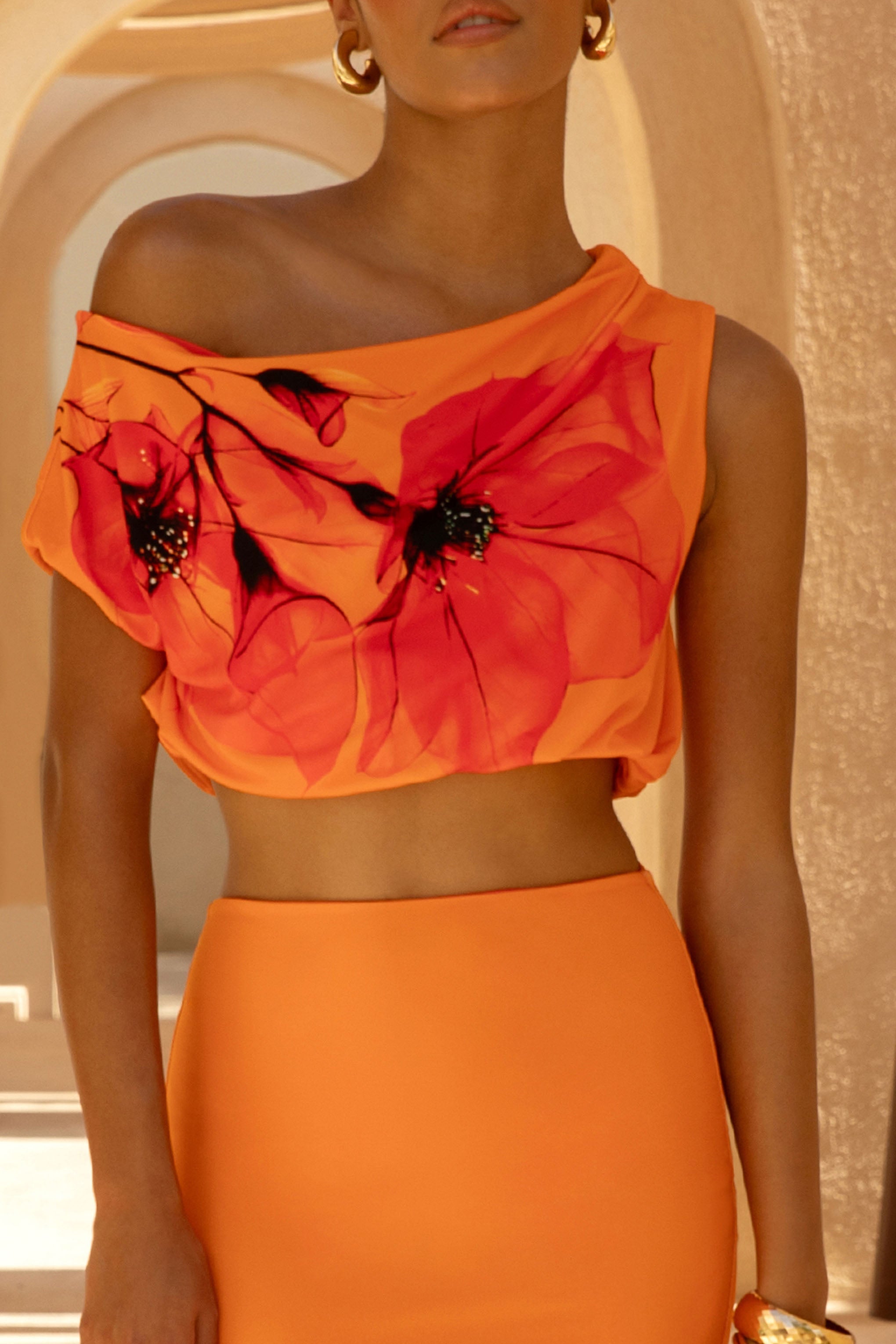 Thalassa | Orange-rotes asymmetrisches Crop-Top mit platziertem Blumenmuster und Rüschen-Detail.